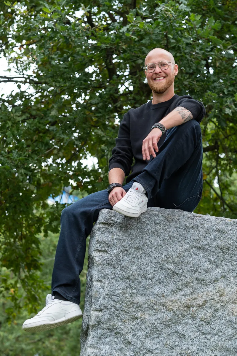 Merlijn Linschooten, fractional CMO for deep tech, sitting on a granite block and laughing